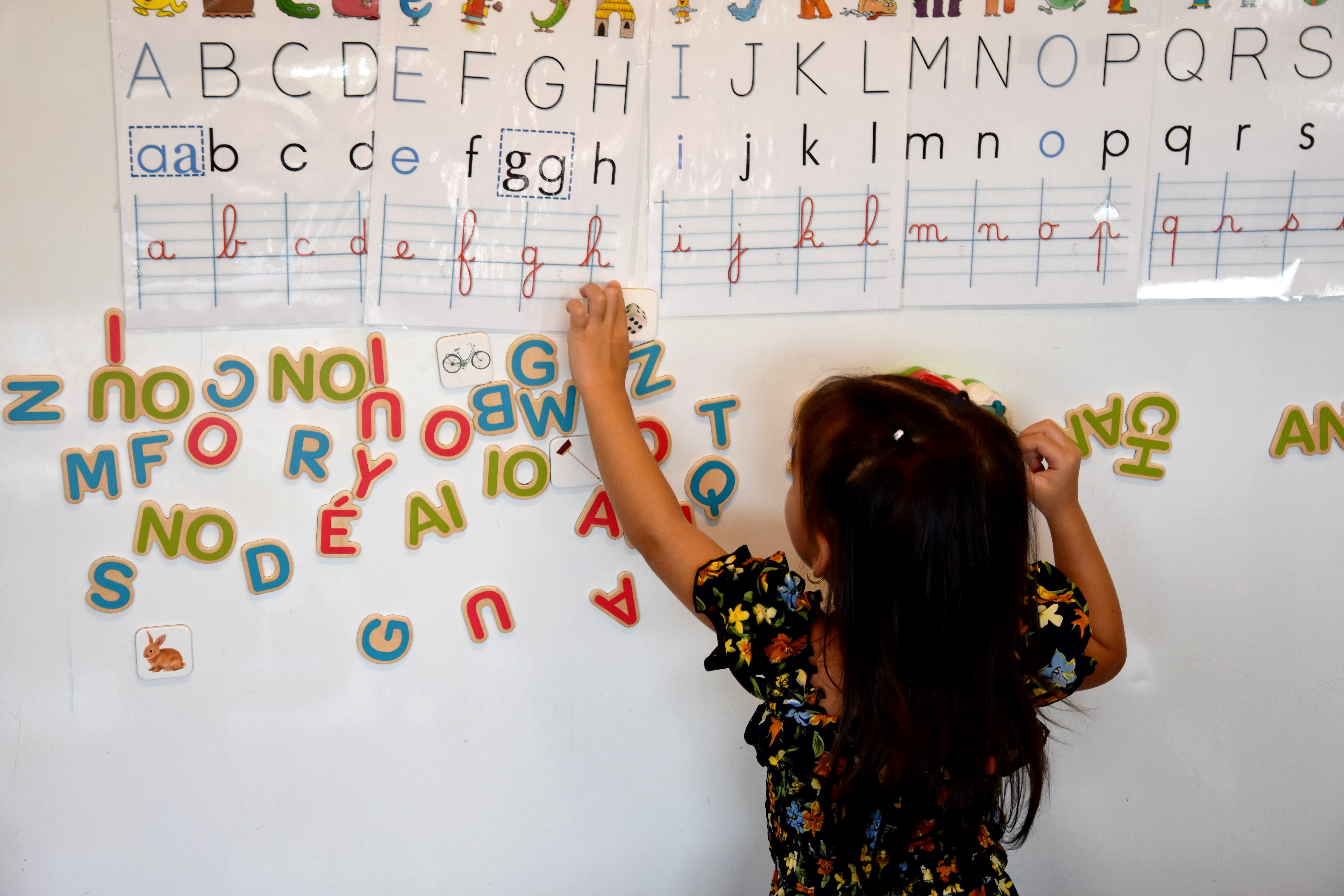 Eleve en maternelle devant un tableau de lettres