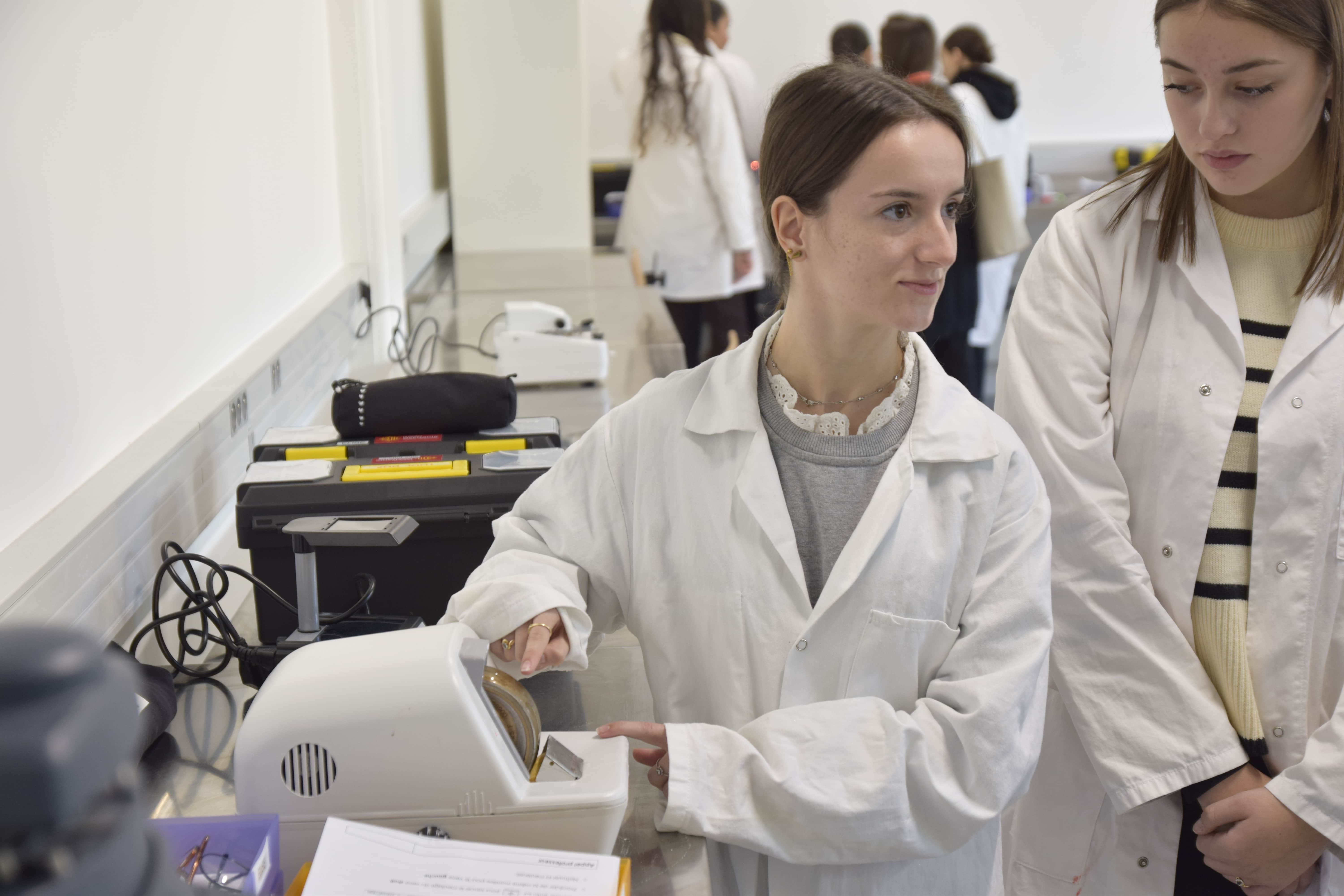 fille en blouse blanche présentant des appareils d'optique