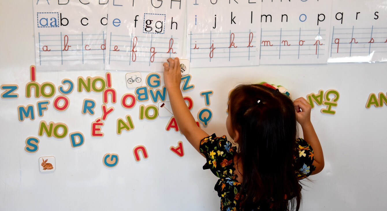 Eleve en maternelle devant un tableau de lettres
