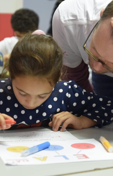 Enseignant aidant une élève à sa table
