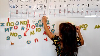 Eleve en maternelle devant un tableau de lettres