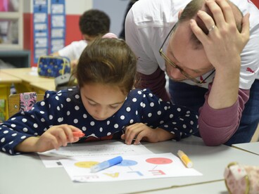 Enseignant aidant une élève à sa table